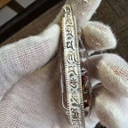 Angled side view of the engraved Zaki Lhamo pendant case