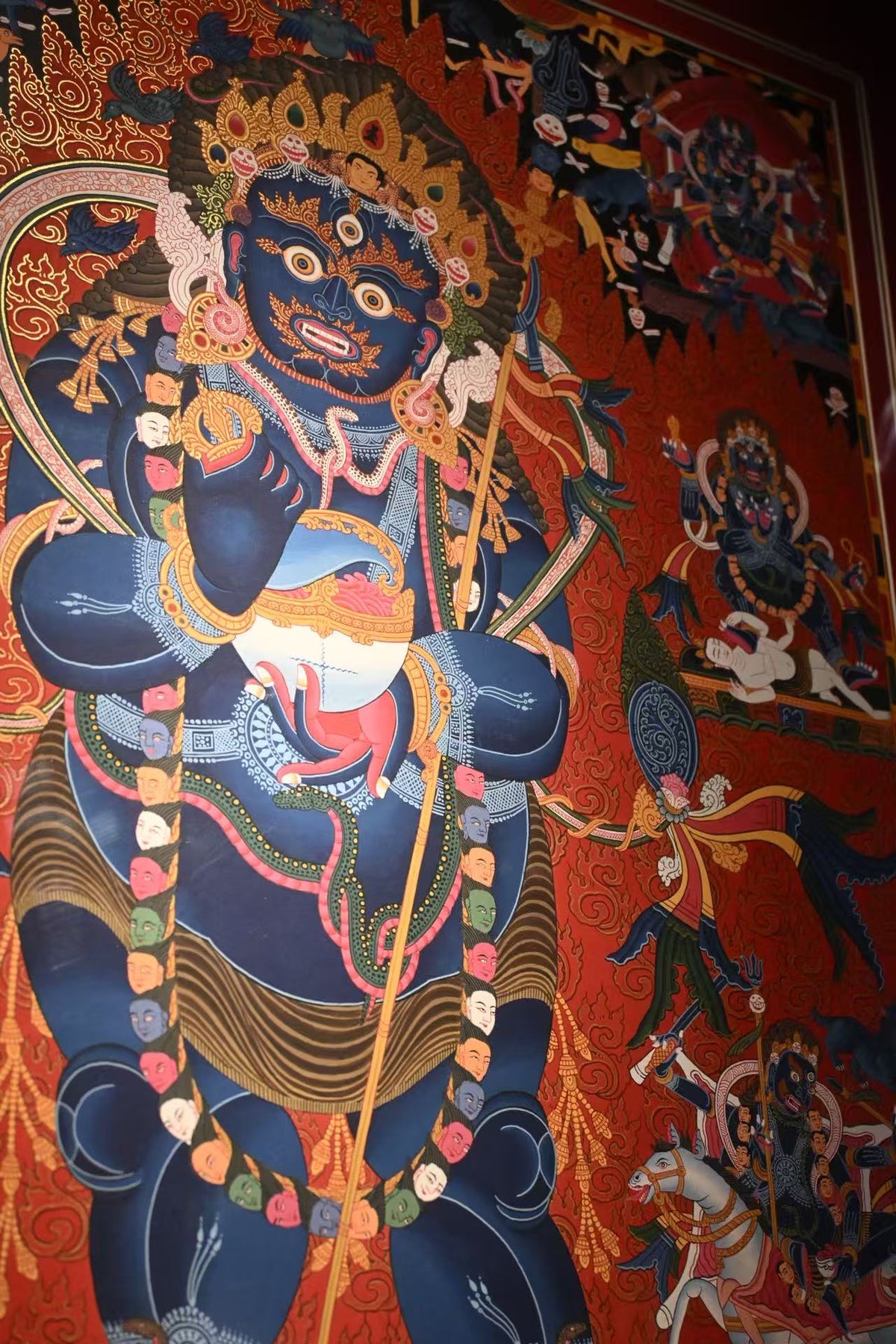 Central blue Mahakala figure on a red-ground thangka