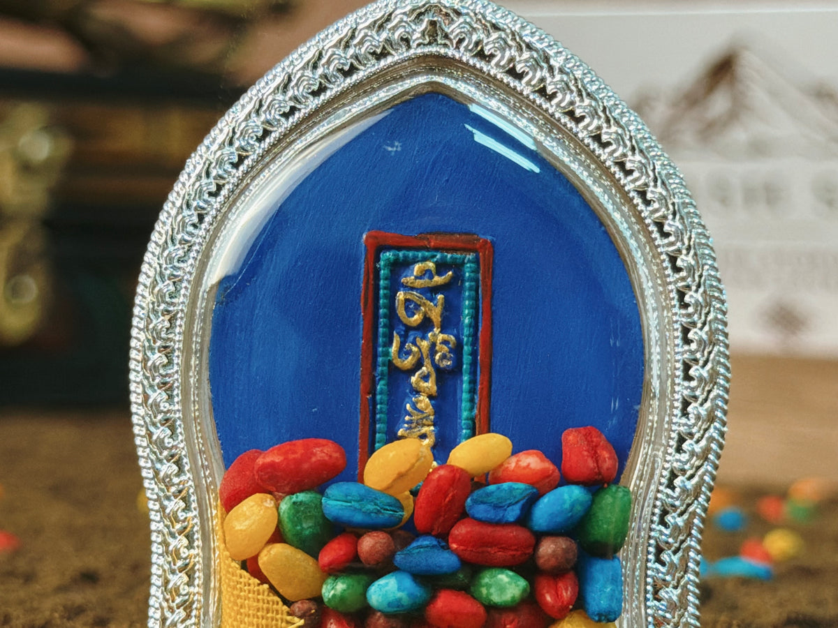 黑財神擦擦嘎烏墜飾，背面透過透明部分可見文字布片與彩色裝藏物。