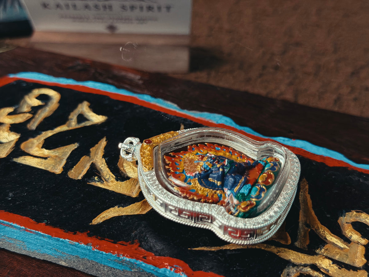 Yamantaka pendant resting at an angle on Tibetan script cloth