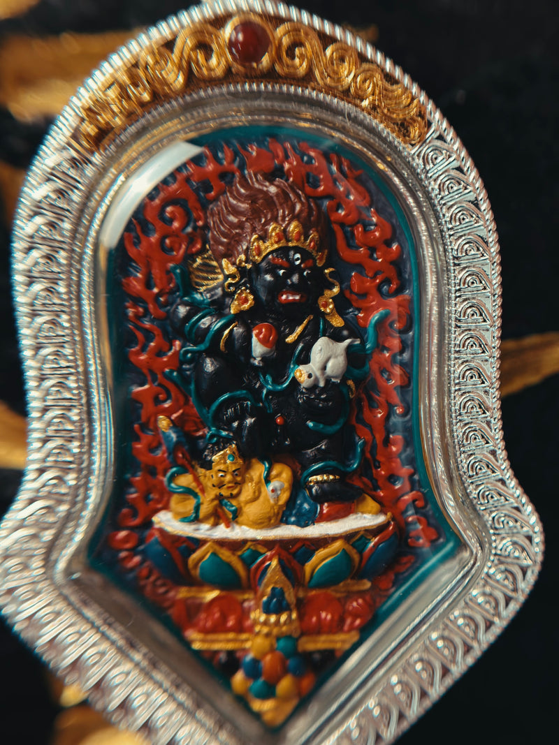 Front detail of Black Jambhala relief in an engraved silver-tone gau case