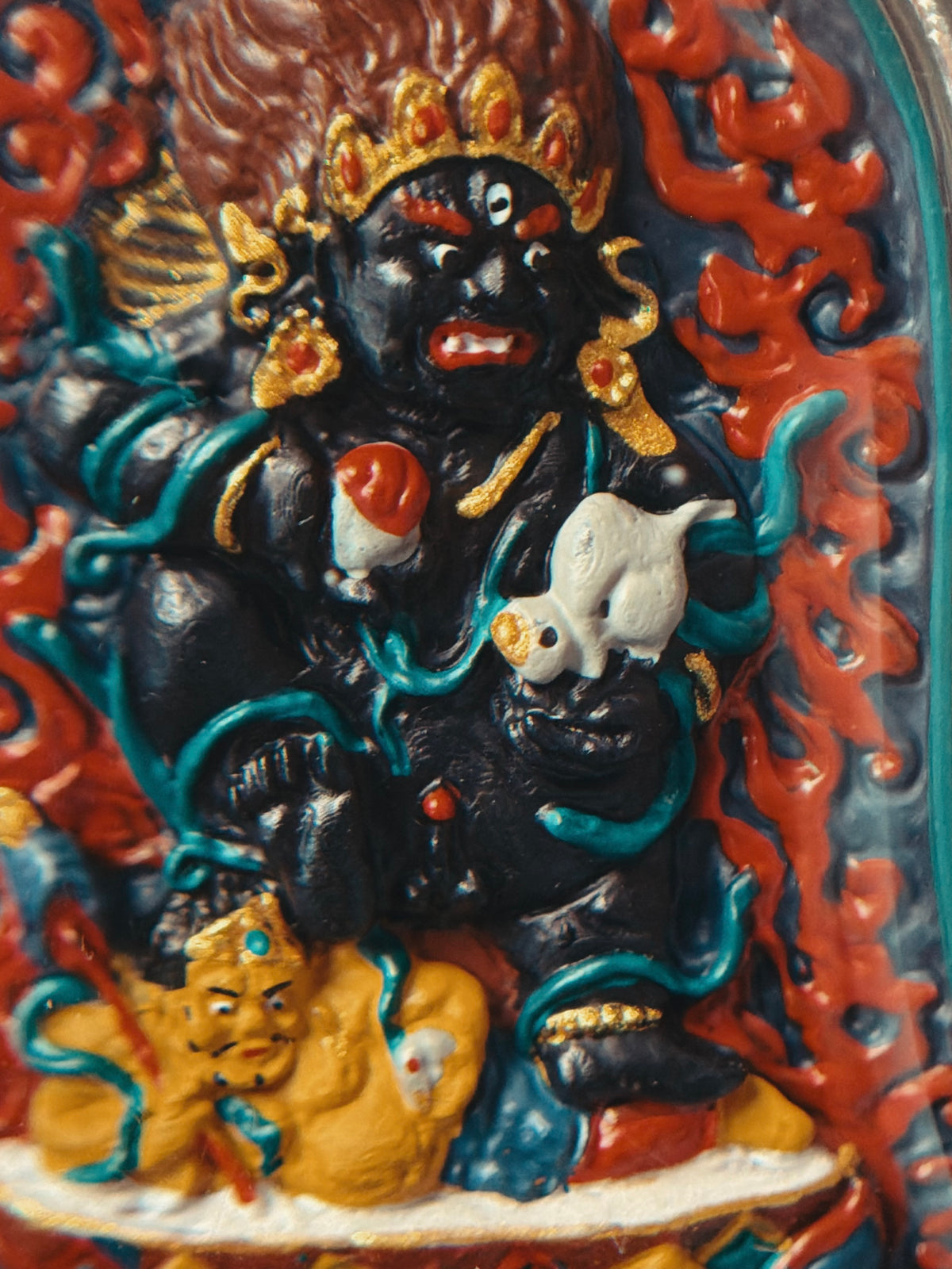 Close-up of the painted Black Jambhala figure and surrounding flames