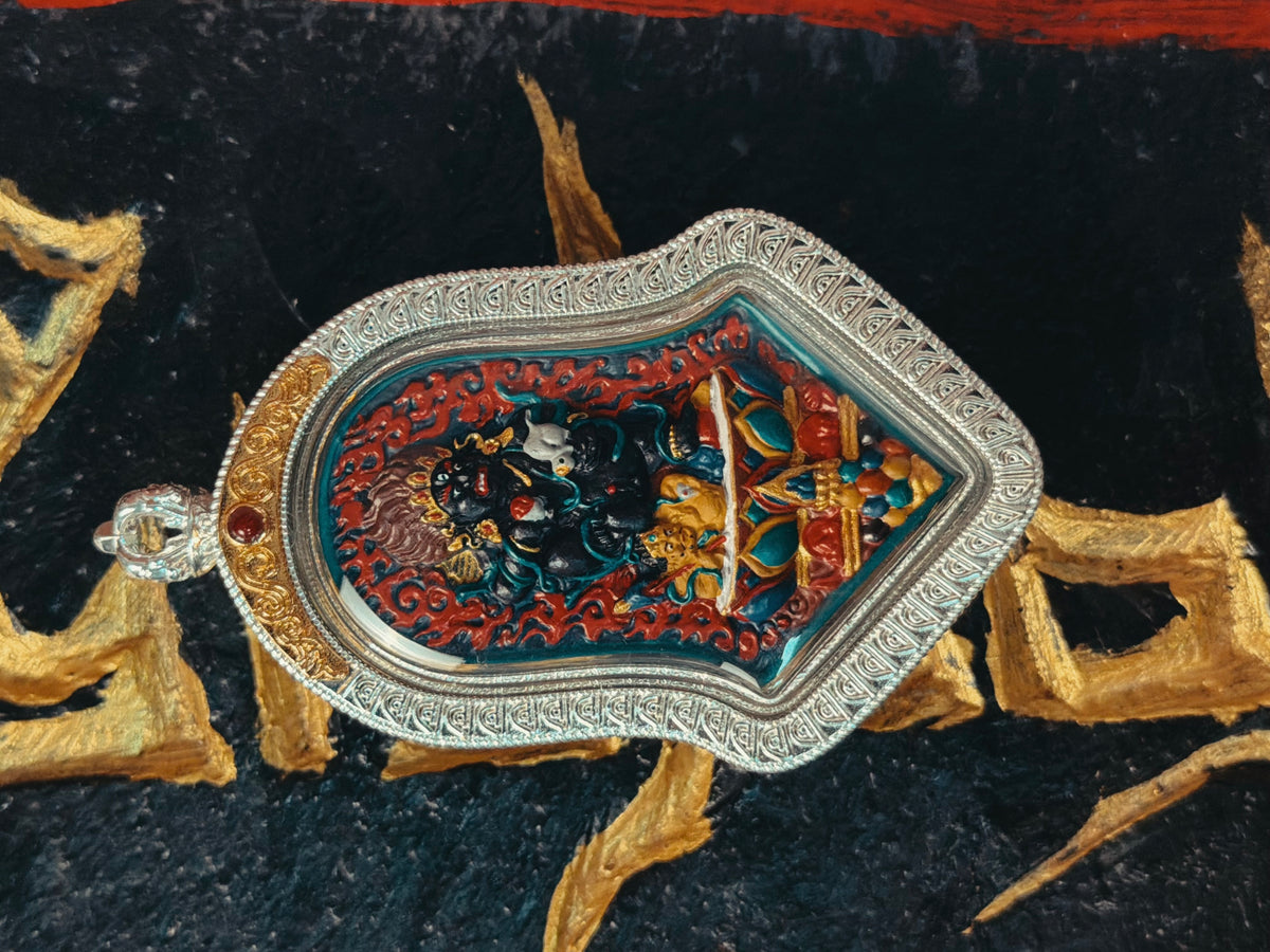 Angled front view of Black Jambhala pendant on Tibetan script cloth